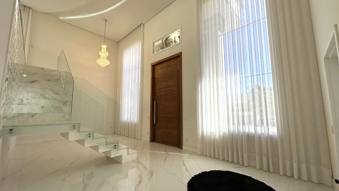 Hall de entrada em pé-direito duplo com porta de madeira maciça e lustre de cristal